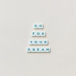 Inspirational text 'Go For Your Dream' made from Scrabble tiles on a plain background.